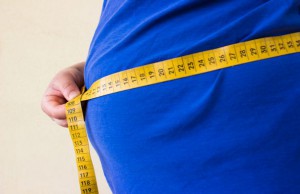 Close up of man holding a tape measure around his waste