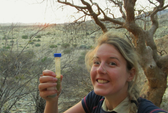 Cassandra holding up a faecal sample in a plastic test tube