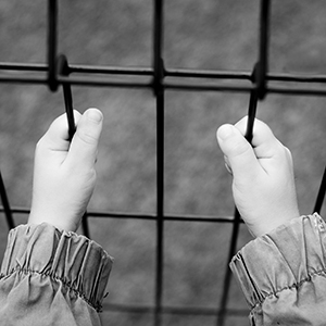 Child's hands holding a iron fence