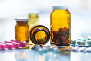 medicines in blister packaging and brown glasses in backlight