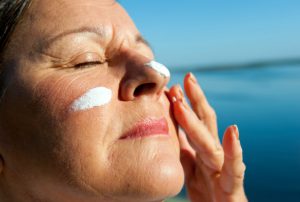 woman applying sun cream to face