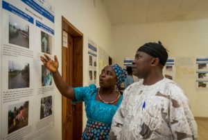 Two people looking at photographs on a wall