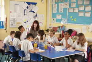 primary school children working round a table with a teacher
