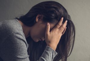 A women with long dark hair holds her head in her hands