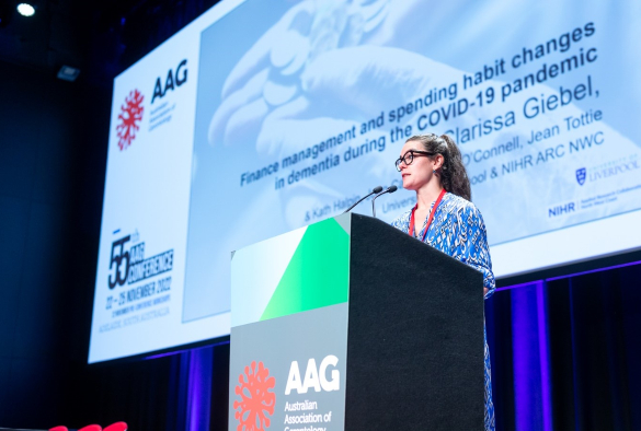 Clarissa standing at a lectern while speaking at the AAG conference