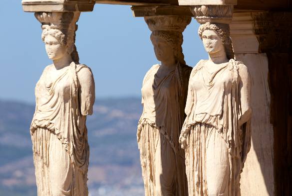 Statues of people on the exterior of the Parthenon, blue sky in background