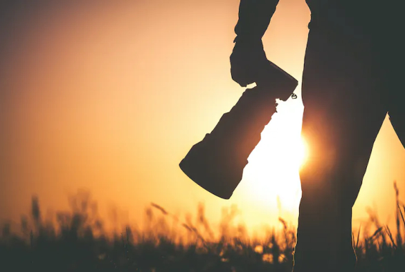 Silhouette of a camera being held by a photographer against a sunset