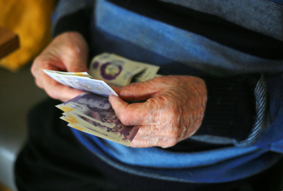 Close up of old man's hands holding banknotes.