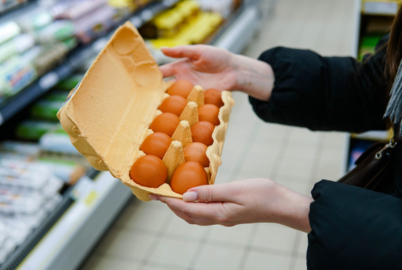 A picture of someone holding eggs in the supermarket