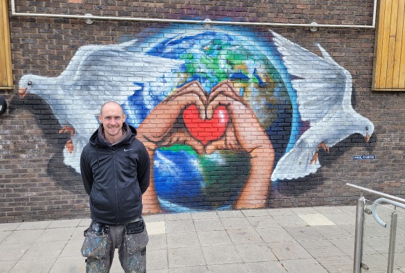 Artist2, Paul Curtis stands with mural on a wall