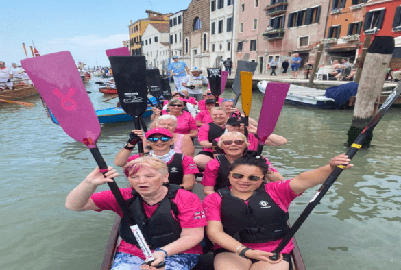 Women on a boat holding paddles up in Venice