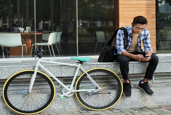 Student on bike on phone campus