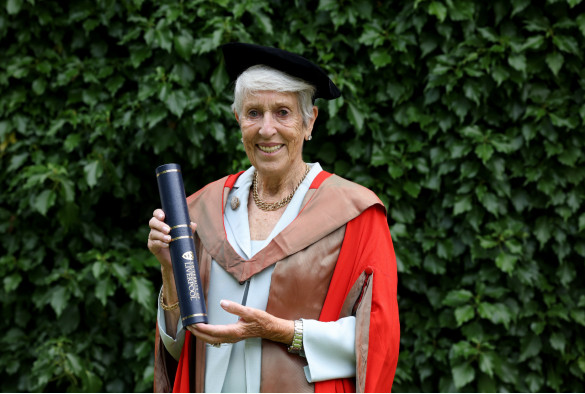 Dame Pauline Harris wearing graduation robes and holding honorary degree scroll