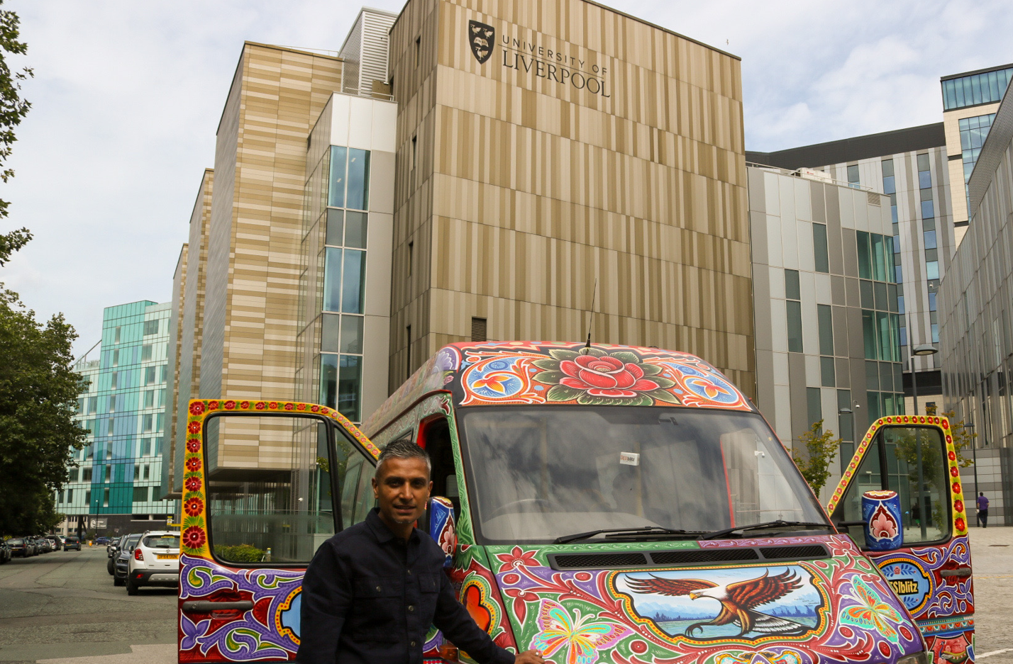 the DESIblitz Punjabi Truck Art bus in front of a building with a university of liverpool sign