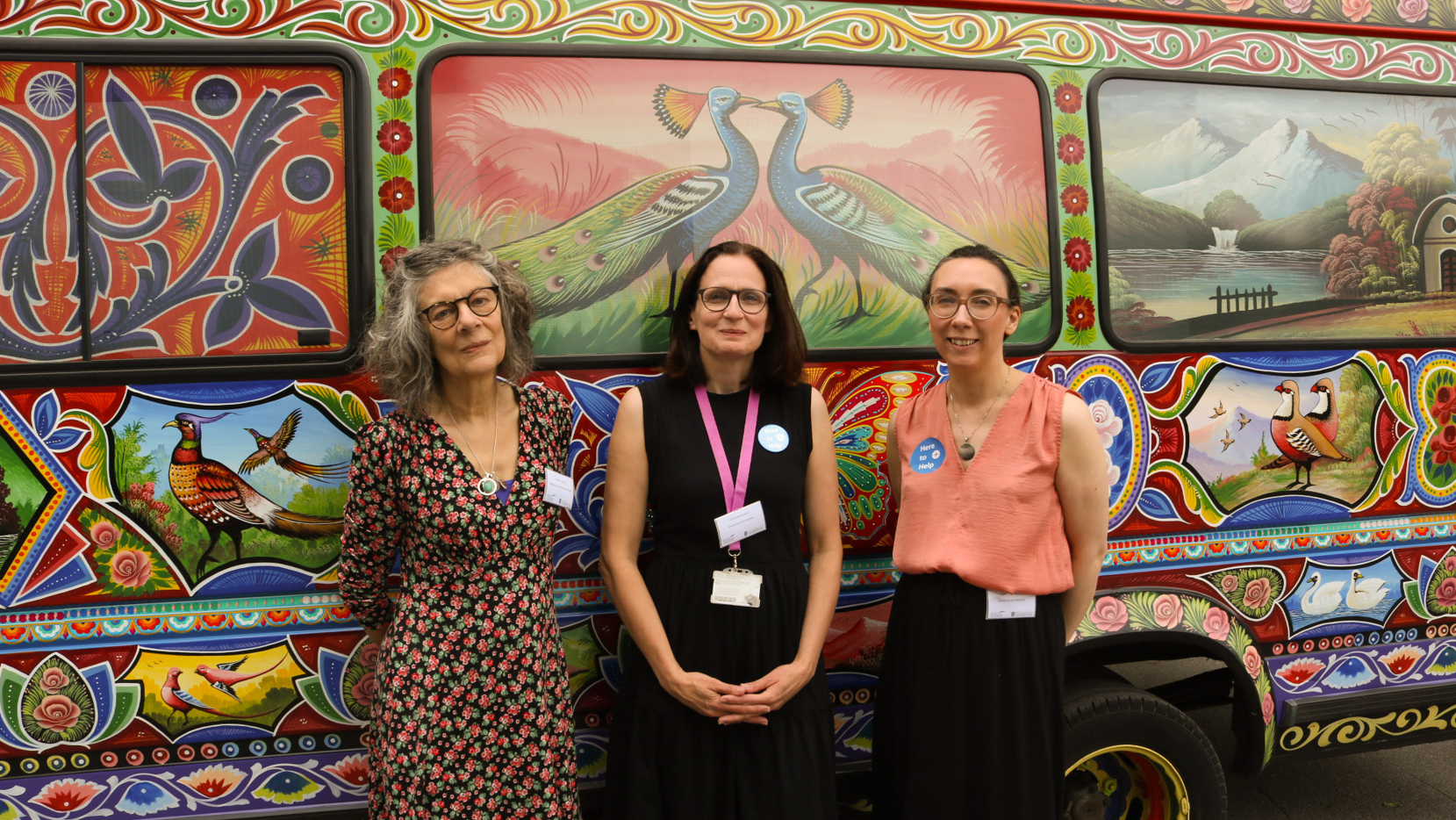 Three women who organised the conference standing in front of an ornately colourful bus 