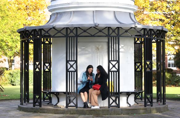 Two students on Abercromby Square looking at a phone - Postgraduate Students (Group Shot) Student News Size