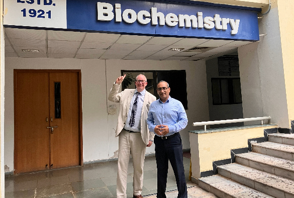 Professor Pat Eyers and Professor Uptal S. Tatu stand underneath sign that says 'Biochemistry'