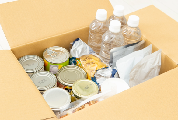 a cardboard box with tins of food in and bottled water for disaster preparation