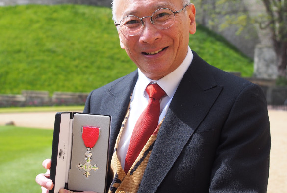 Headshot of Professor Saye Khoo holding his MBE medal