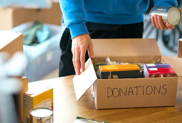 Close Up Of Male Charity Volunteer Working At Food Bank Unpacking Donations