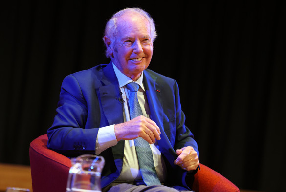 Sir Peter Rigby seated on red armchair during q&a session