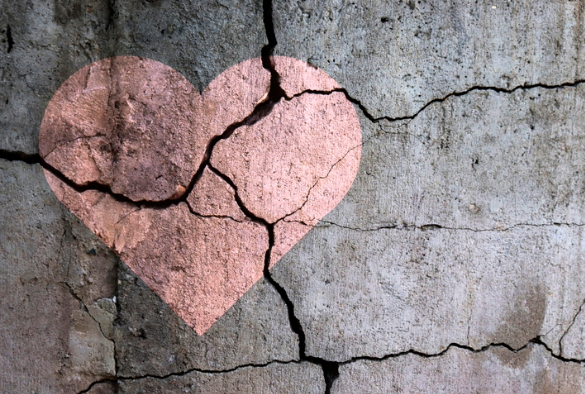 A picture of a heart on a wall with cracks in