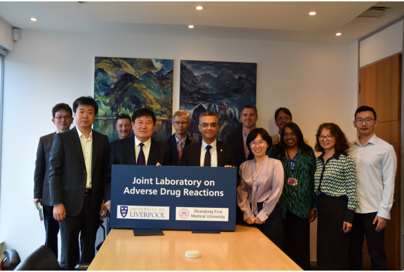 Group photo of researchers from both institutions standing in meeting room