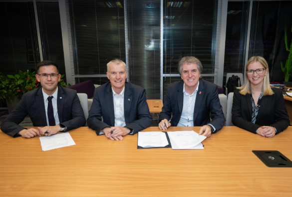 Four people round a table signing an MoU