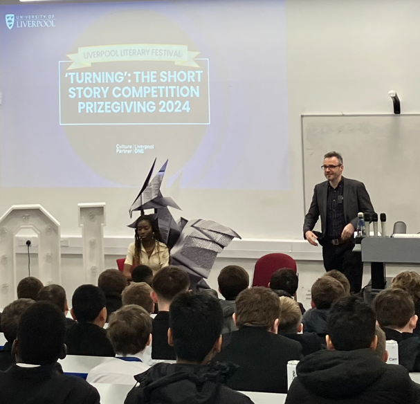 Greg Lynall at the front of the lecture hall speaking to school students