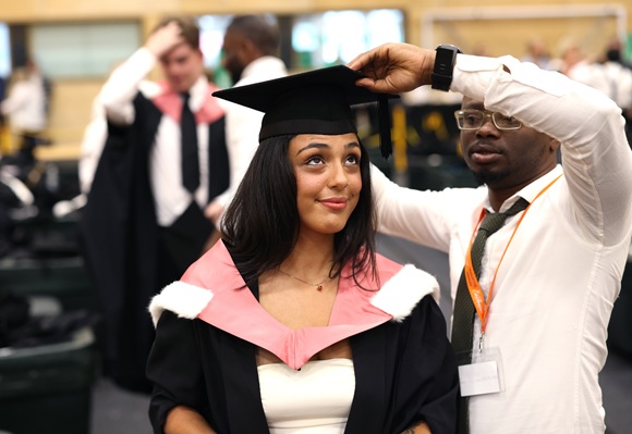 a female student puts on her cap and gown