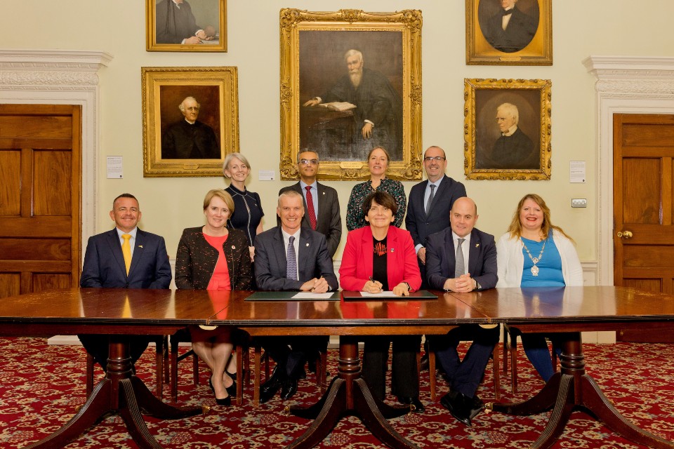 Attendees at signing table, paintings in background