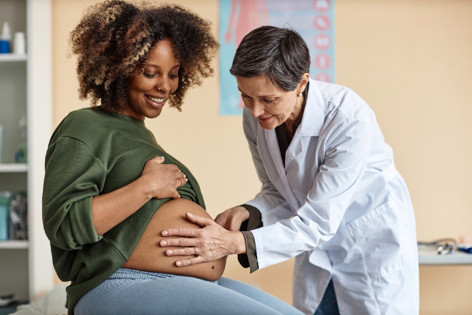 Pregnant woman having examination from clinician