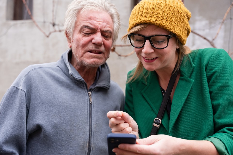 Social worker assisting senior man using smartphone - stock photo