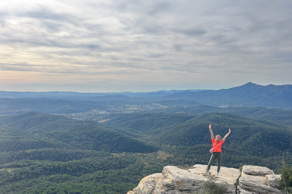Student standing on a high rock with Catalonian mountain range in background